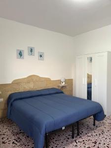 ein Schlafzimmer mit einem blauen Bett und einer weißen Wand in der Unterkunft MONOLOCALE LA GROTTA in Capilungo