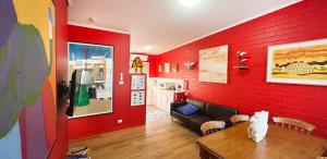 a living room with red walls and a couch and a table at & Art Motel in Tootgarook