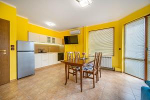 a kitchen with yellow walls and a table and chairs at Апартамент Слънчев Ден in Balchik