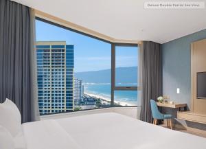 a hotel room with a bed and a large window at Awaken Da Nang Hotel in Danang