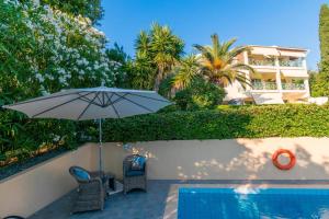 a patio with an umbrella and chairs next to a swimming pool at Blue Coast Suites - Seaside Retreat with Pool in Exclusive Kommeno in Kommeno
