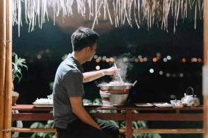 a man cooking food in a pot on a table at Baan 2 Dao Farmstay in Chiang Dao
