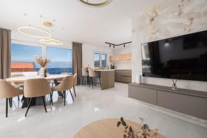 a living room with a large television and a dining room at Villa SUNSET II with private pool and beautiful sea view in Vrbnik