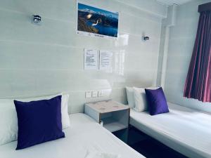 two beds in a room with purple and white pillows at KATHMANDU GUEST HOUSE in Hong Kong +35 photos