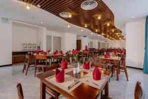 un restaurante con mesas de madera y sillas con servilletas rojas en River Way Hotel Ha Long, en Ha Long