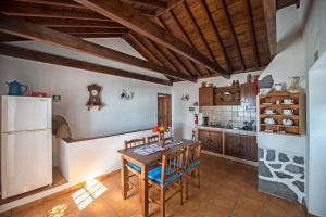 a kitchen with a wooden table and a refrigerator at Casas do Capelo in Varadouro