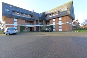 a large brick building with cars parked in a parking lot at Entennest am Dorfteich in Wenningstedt