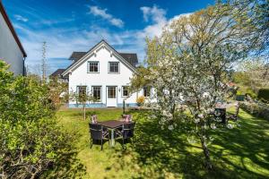 a white house with a table and chairs in the yard at Ferienwohnung 4 in Groß Zicker
