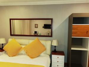 Schlafzimmer mit einem weißen Bett und einem Spiegel in der Unterkunft Lotus Guest House in Johannesburg
