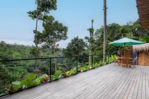 a wooden deck with a table and an umbrella at Sebatu Hill Cottage by Great Bali Villas in Tampaksiring +21 photos