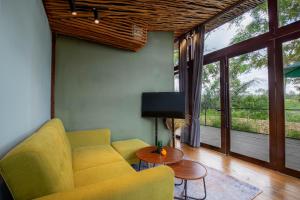 a living room with a yellow couch and a tv at Sebatu Hill Cottage by Great Bali Villas in Tampaksiring