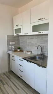 a kitchen with white cabinets and a sink at Apartman Dina in Sanski most +8 photos