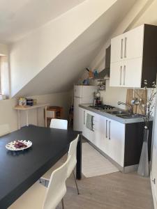 a kitchen with a black table and white cabinets at I Pini Apartment in Eraclea Mare