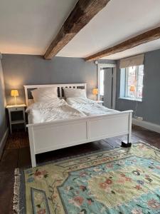 a bedroom with a white bed and a rug at Millers Kate mit Elbblick in Lauenburg