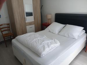 a bedroom with a bed with white sheets and a chair at Appartement tout confort hyper centre in Royan