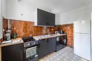 a kitchen with black cabinets and a white refrigerator at Le Marignan- Studio plein centre in Cassis