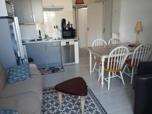 a kitchen and a living room with a table and chairs at Appartement tout confort hyper centre in Royan