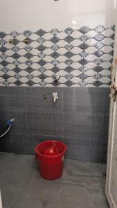 un secchio rosso in un bagno con una parete piastrellata di A P GRAND HOTEl a Kānpur