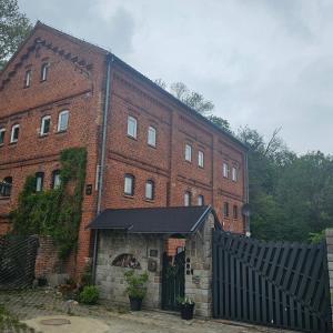 a large brick building with a black gate in front of it at Krzywa Apartamenty in Lidzbark Warmiński