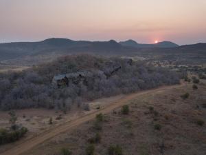 an aerial view of a dirt road in the desert with the sunset at Tshukudu Bush Lodge in Ledig