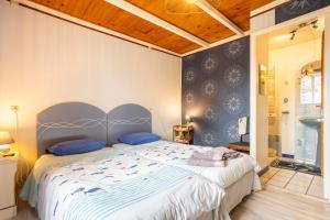 a bedroom with a large bed with blue pillows at La ferme de séjour du Cosquer in Beuzec-Cap-Sizun