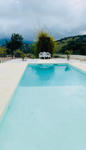 a large swimming pool with two white chairs next to it at Cigarral Bramasole in Los Navalucillos +45 photos