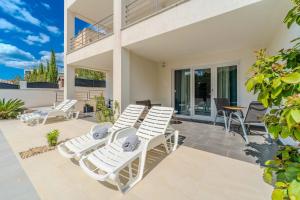 a patio with white lounge chairs and a table at Villa Carlotta in Zadar
