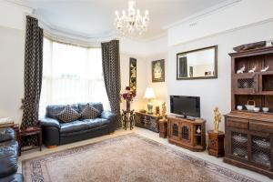 a living room with a couch and a television at Arden Park Ensuite Rooms in Stratford-upon-Avon