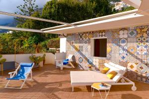 a patio with chairs and a mosaic wall at Celebrity Suite - Big Terrace on the Sea in Praiano
