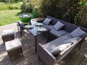 ein Sofa und einen Tisch auf einer Holzterrasse in der Unterkunft Maison ecologique avec jardin in Elne