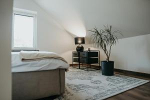 a bedroom with a bed and a potted plant at Castle Lakes - Apartamenty in Grzymalin
