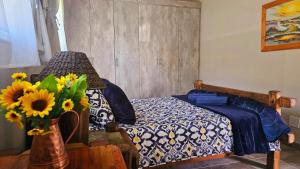 a bedroom with a bed and a vase of sunflowers at CasaMari guesthouse in Pretoria