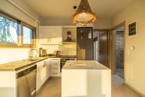 a kitchen with white cabinets and a sink and a chandelier at Jarko Luxury Houses in Argoulidhés