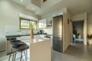 a kitchen with white counters and a stainless steel refrigerator at Jarko Luxury Houses in Argoulidhés