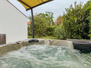 a jacuzzi in a backyard with an umbrella at maison au calme la chaume 6 personnes in La Chaume