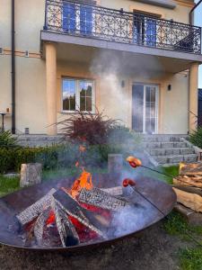 a fire pit with a surfboard in front of a house at Apartamenty Agroturystyczne Papiernia in Niedźwiedź