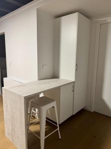Un escritorio con un taburete en una habitación con armarios blancos. en Wanaka Matai Studio, en Wanaka