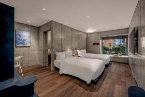 two white beds in a room with wooden floors at Oday Stay Boutique Hotel Da Nang - 2 Minutes to Dragon Bridge in Danang