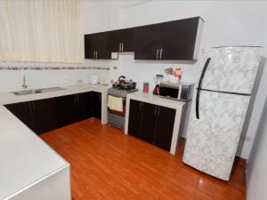 cocina con armarios blancos y negros y nevera en Fully furnished 3-Bedroom Apt In Tarapoto, en Tarapoto