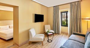 a hotel room with a couch and a bed at NH Collection Cáceres Palacio de Oquendo in Cáceres