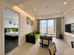 a living room with a green couch and a bedroom at Sunset town Phú Quốc in Phú Quốc