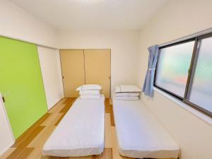 ein Krankenzimmer mit drei Betten und einem Fenster in der Unterkunft 友縁の家Destined Bonds Haven西巣鴨 in Tokio