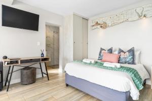 a bedroom with a bed and a desk with a television at Zaria Sun Cottage by Host Agents in Gordonʼs Bay