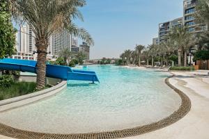 a pool with a slide in a resort with palm trees at Dune Escape Stylish Poolside Courtyard Retreat in Dubai