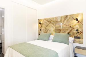 ein Schlafzimmer mit einem weißen Bett mit grünen Kissen in der Unterkunft Un acogedor complejo compuesto de 5 apartamentos in Barbate