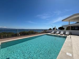 a swimming pool with chairs and the ocean in the background at Appartement Eden A sanguinaires vue mer avec piscine résidence in Ajaccio