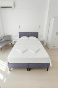 a white bedroom with a bed and a chair at R HOUSE HOTEL in Bodrum City
