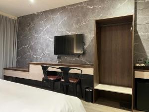 a hotel room with a bed and two chairs and a tv at Saint Hostel in Beigang