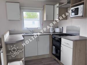 a kitchen with white cabinets and a stove top oven at 3 bedroom Static Home by White Horse, Seal Bay in Selsey