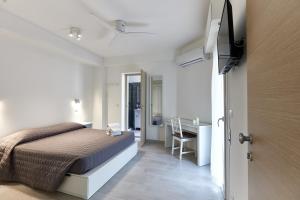a white bedroom with a bed and a desk at Garnì Stella Marina in Cervia